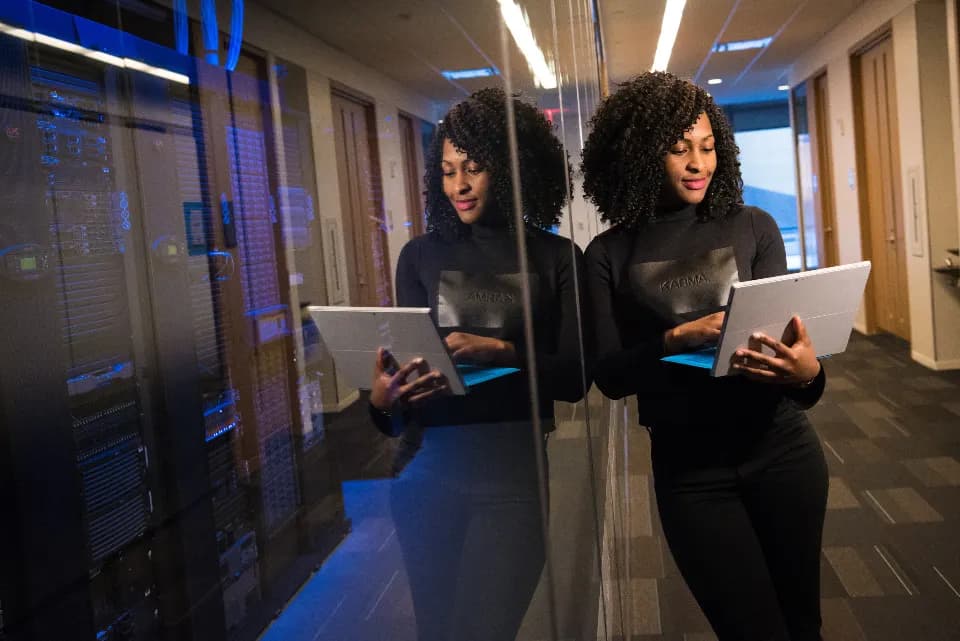 A woman checking a tablet in a corridor of server racks